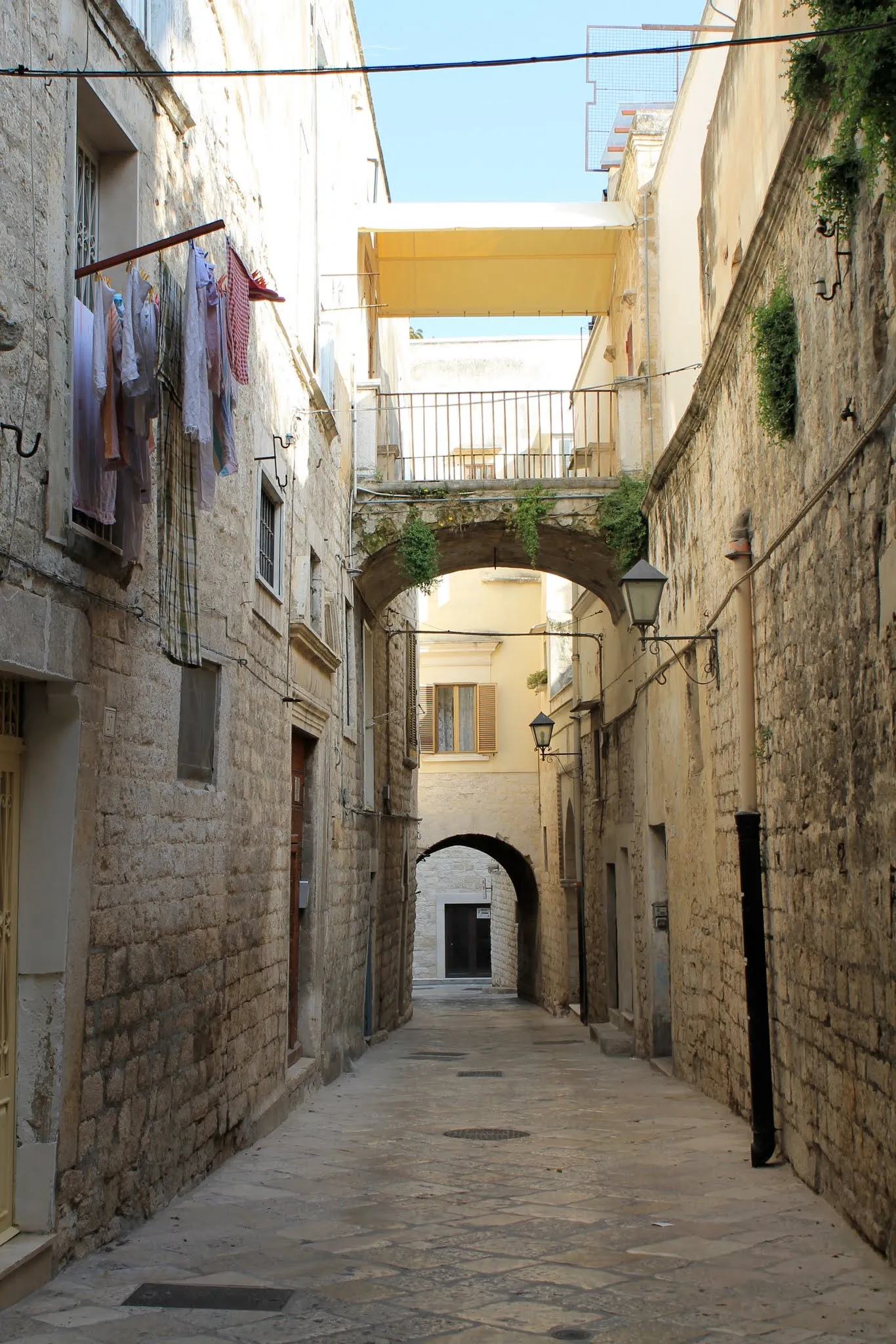 Vicolo in pietra del centro storico di Trani con archi e lampioni